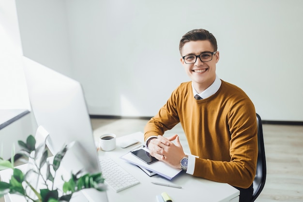 Young successful brunette man sitting at his office and working with papers.