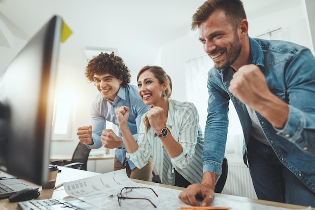 Young successful business people celebrating success while working on a new project in the casual office.