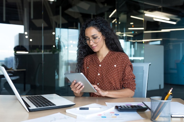 Young successful business woman working inside modern office building hispanic woman using tablet