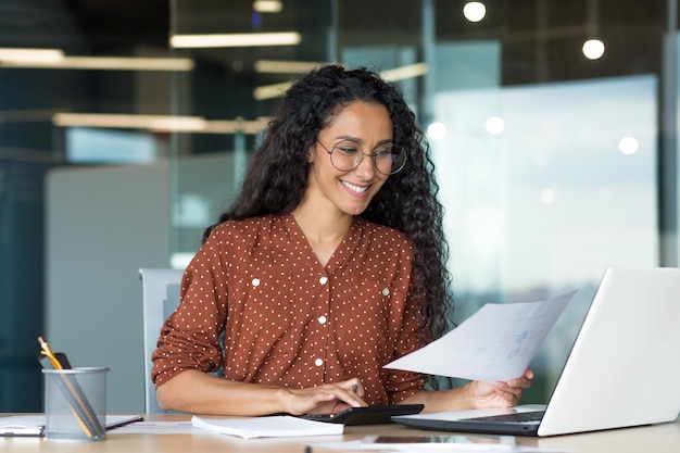 Young successful businesswoman behind paperwork hispanic woman working with documents and contracts