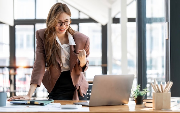 Young successful businesswoman raising her hands up and laughing with happinessx9