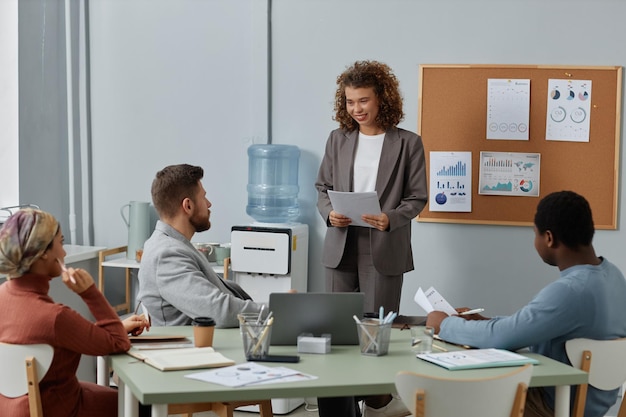 Young successful female broker with documents talking to one of colleagues