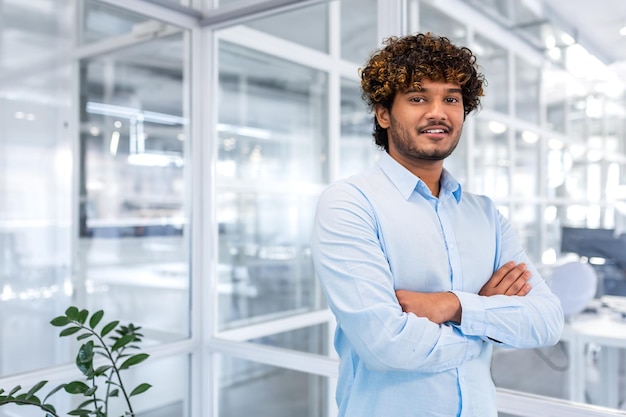 Young successful hispanic businessman in the middle of the office portrait of happy and satisfied