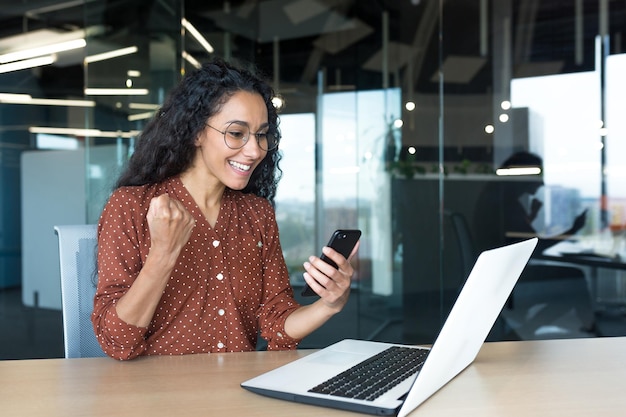 Young successful hispanic businesswoman working inside modern office female worker using laptop