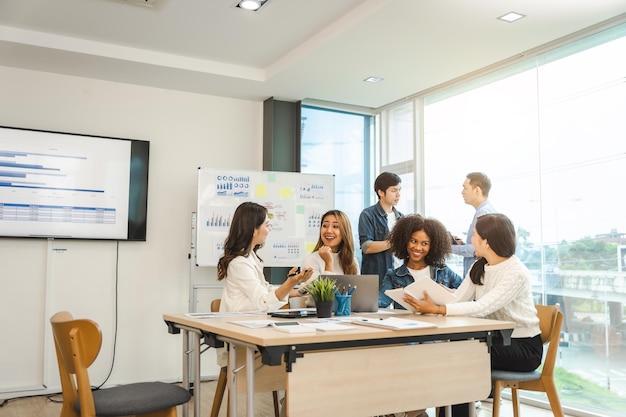 Young and successful mixed race asian business people working on project together sitting at table in boardroom