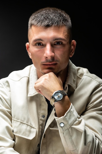 Young successful stylish man Classical portrait of a businessman dressed in a jacket with a watch on his hand