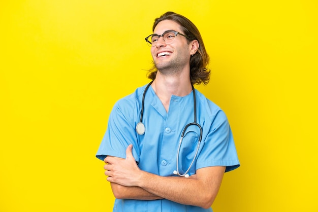 Young surgeon caucasian man isolated on yellow background happy and smiling