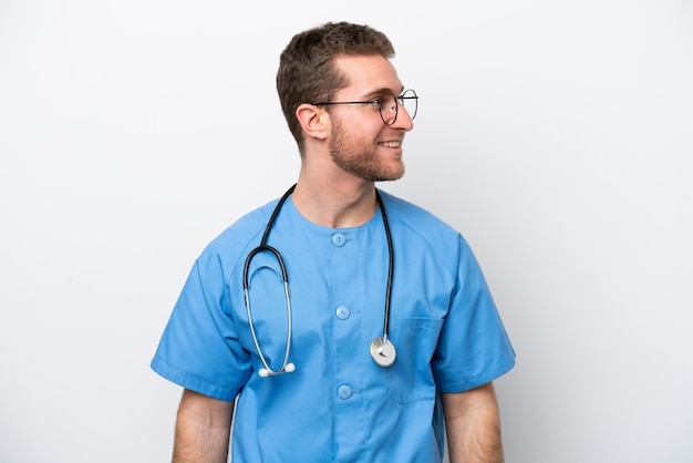 Young surgeon doctor caucasian man isolated on white background looking side