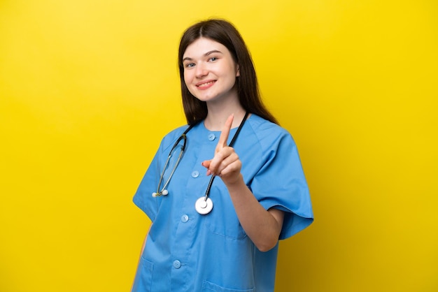 Young surgeon doctor Russian woman isolated on yellow background showing and lifting a finger