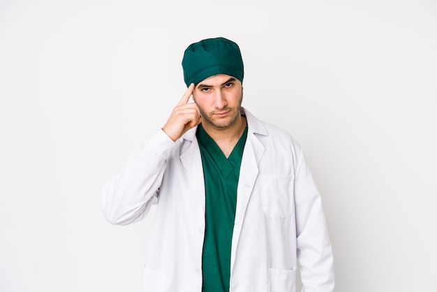 Young surgeon man pointing temple with finger