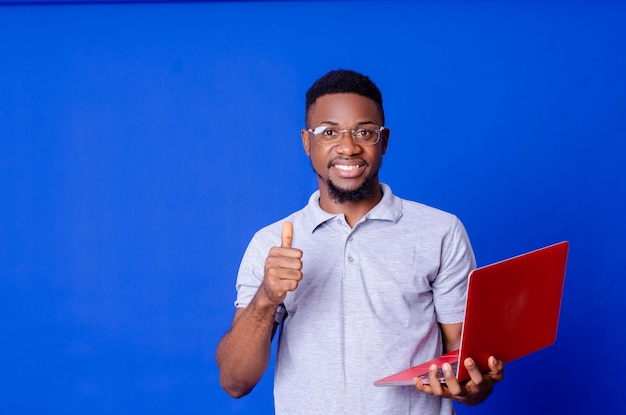 Young surprised african american man standing and using laptop computer