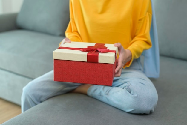 Photo young surprised muslim woman opening a gift box in living room