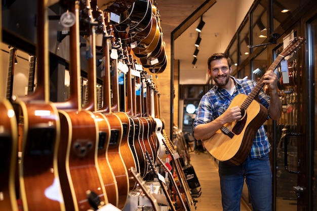 Young talented musician testing new guitar instrument in music shop.