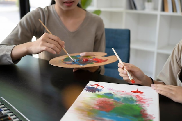 Young teacher painting pictures with little girl in art class