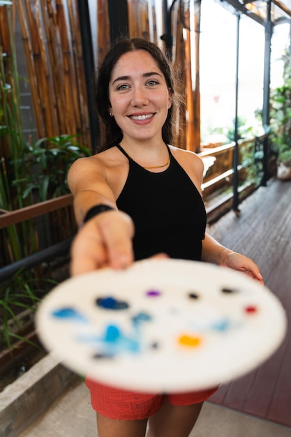 Photo young teacher smiling at the camera showing the color palette in a painting workshop vertical