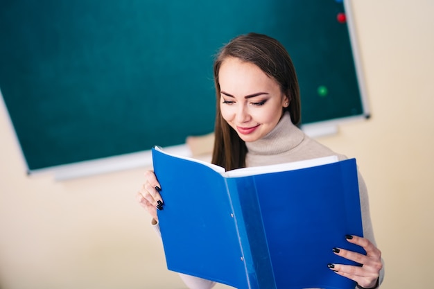 Young teacher with a folder in the classroom. Educational concept.