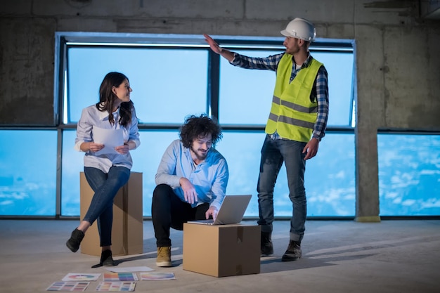 young team of business people in group, architect and engineer on construction site checking documents and business workflow using laptop computer in new startup office