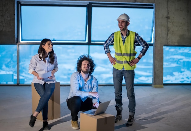 young team of business people in group, architect and engineer on construction site checking documents and business workflow using laptop computer in new startup office