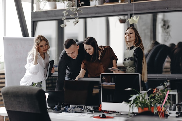 Young team works at the desks with a computer and laptops in a light modern open space office