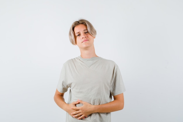 Young teen boy having abdominal pain in t-shirt and looking unwell. front view.