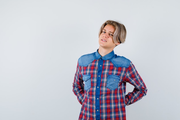 Young teen boy suffering from backache in checked shirt and looking bothered