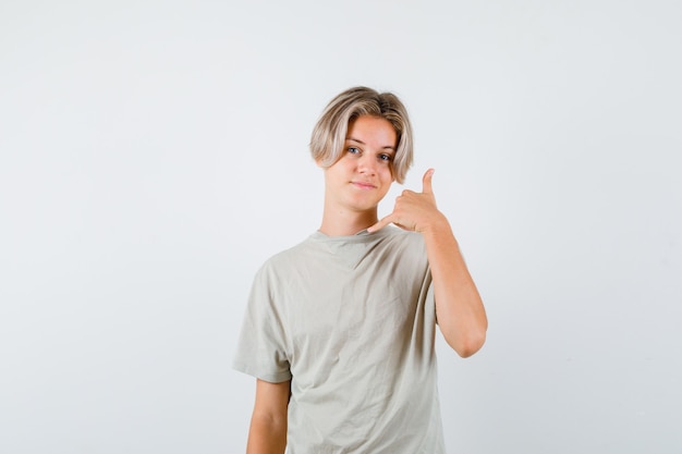 Young teen boy in t-shirt showing phone gesture and looking confident