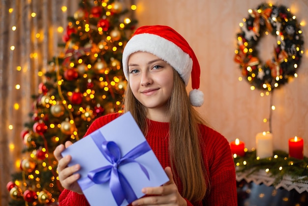 Young teenage girl holds Christmas present box in decorated living room Christmas present concept