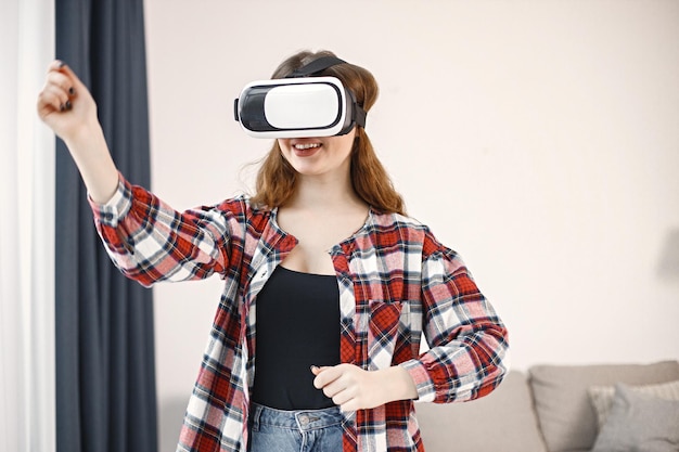 Young teenage girl standing in living room wearing a virtual reality glasses