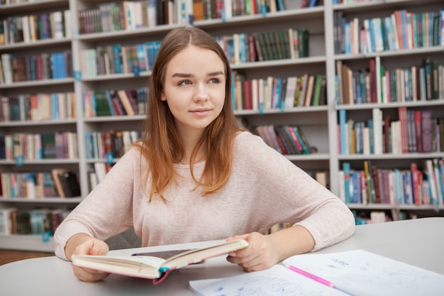 Young teenage girl studying at the library