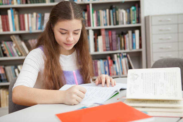 Young teenage girl studying at the library