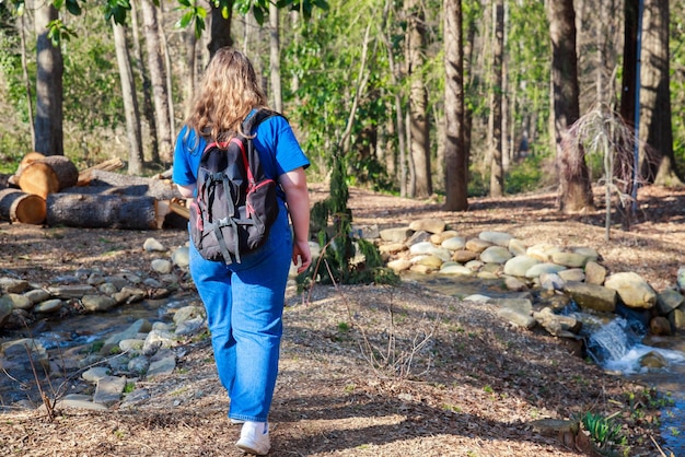 Young teenage girl with backpack hiking through forest