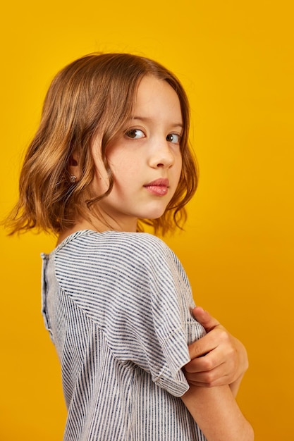 Young Teenage Schoolgirl Against a Vibrant Yellow Background in Studio Setting