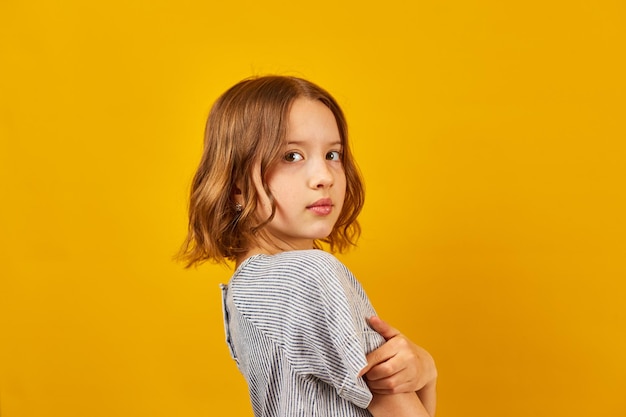 Young Teenage Schoolgirl Against a Vibrant Yellow Background in Studio Setting