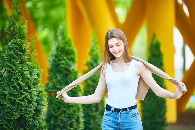 Young teenage woman walking down the street in jeans and a sweater on a summer day The concept of youth fashion Urban lifestyle