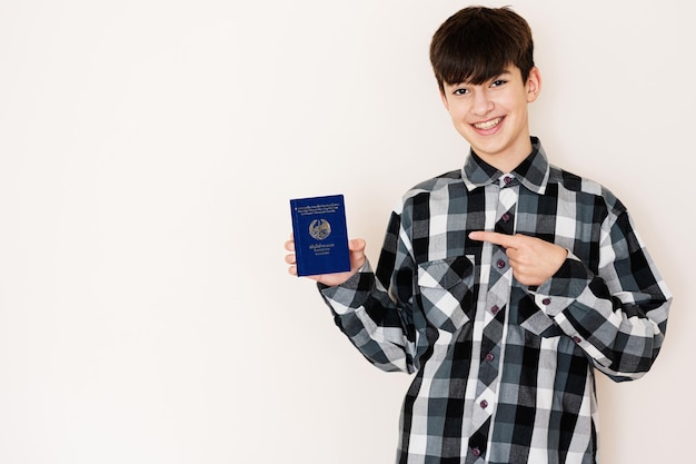 Young teenager boy holding Laos passport looking positive and happy standing and smiling with a confident smile against white background