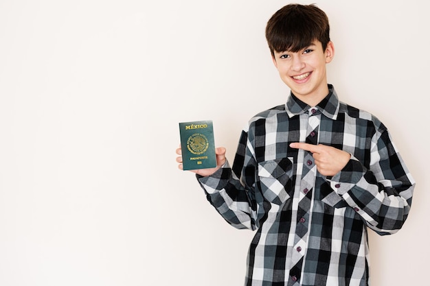 Young teenager boy holding Mexico passport looking positive and happy standing and smiling with a confident smile against white background