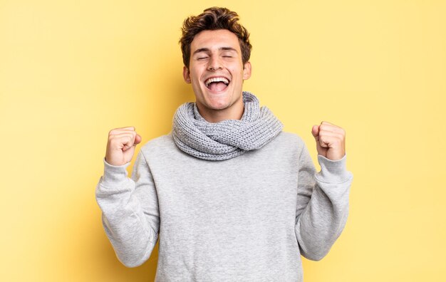 Young teenager boy looking extremely happy and surprised, celebrating success, shouting and jumping