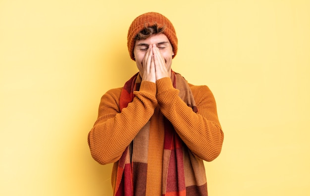 Young teenager boy looking happy, cheerful, lucky and surprised covering mouth with both hands