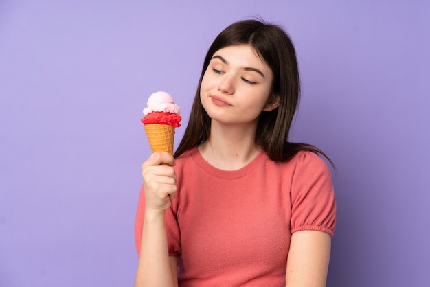 Young teenager girl holding a cornet ice cream over purple wall