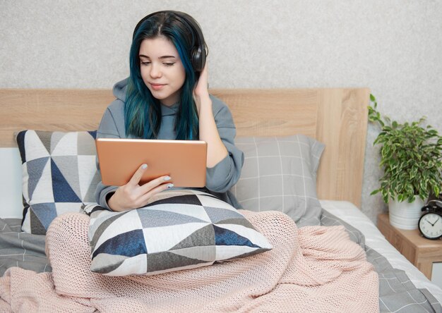 Young teenager girl with blue hair tablet and  headphones