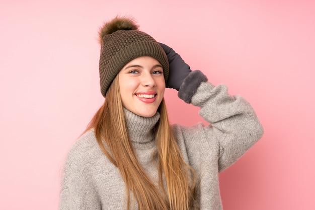 Young teenager girl with winter hat over isolated pink laughing