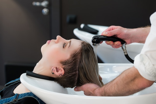 Young teenager in hairdressing salon washing hair