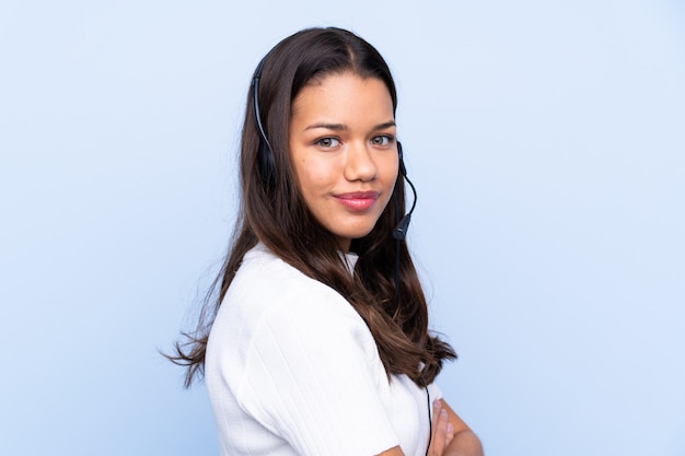 Young telemarketer woman over isolated wall