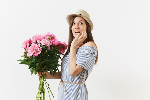 Young tender woman in blue dress, hat holding bouquet of beautiful pink peonies flowers isolated on white background. St. Valentine's Day, International Women's Day holiday concept. Advertising area.