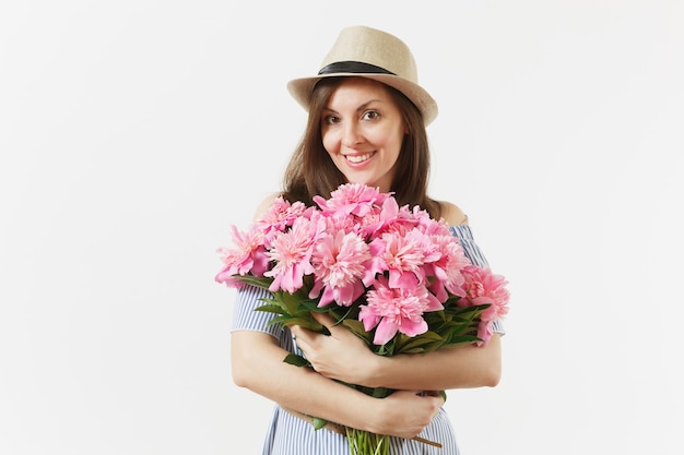 Young tender woman in blue dress, hat holding bouquet of beautiful pink peonies flowers isolated on white background. St. Valentine's Day, International Women's Day holiday concept. Advertising area.