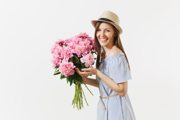 Young tender woman in blue dress, hat holding bouquet of beautiful pink peonies flowers isolated on white background. St. Valentine's Day, International Women's Day holiday concept. Advertising area.