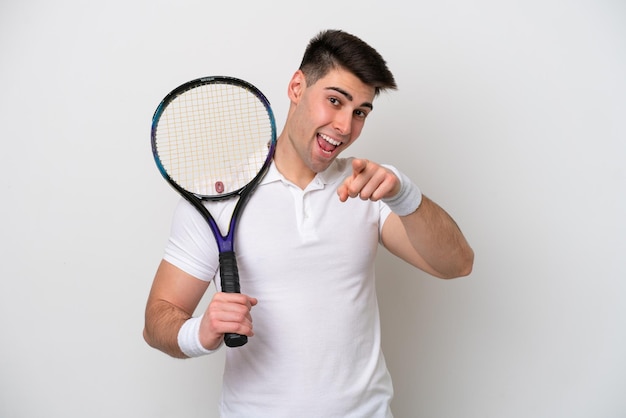 Young tennis player man isolated on white background surprised and pointing front