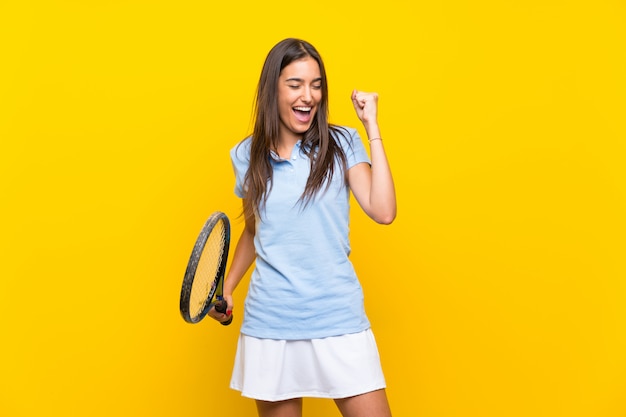 Young tennis player woman over isolated yellow wall