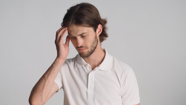 Young thoughtful man looking serious trying to remember what he must to do isolated on gray background Deep in thoughts