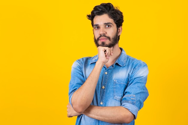 Young thoughtful student boy on yellow background young man thinking and having an idea